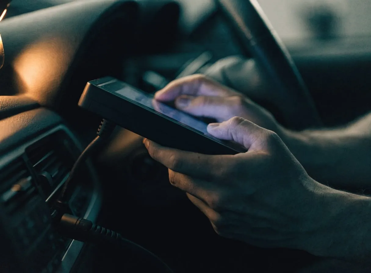 A technician reading fault codes on a diagnostic tablet plugged into a car.